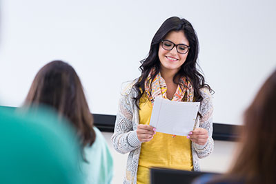 Hip young woman reading report to college class